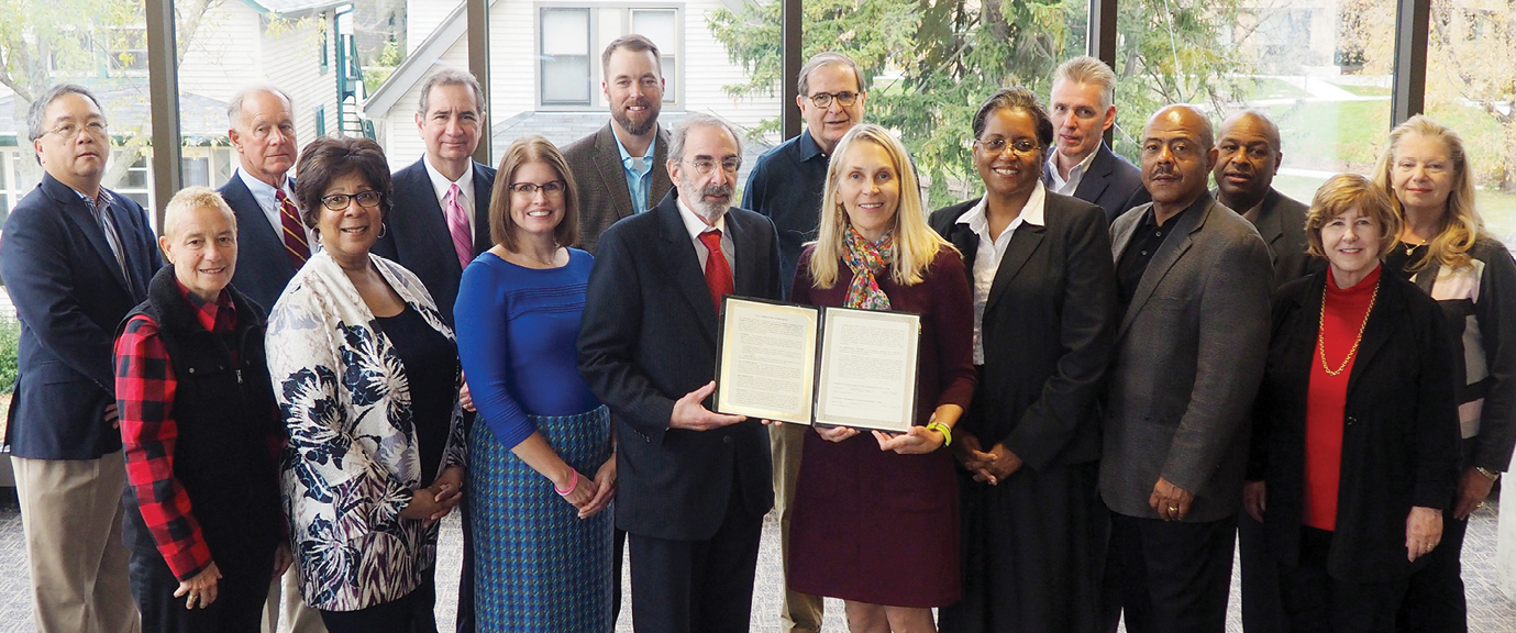 group photo from the 2018 visit to NCBE offices that formalized the NCBE/CLEO agreement, which is being held at the center of the group