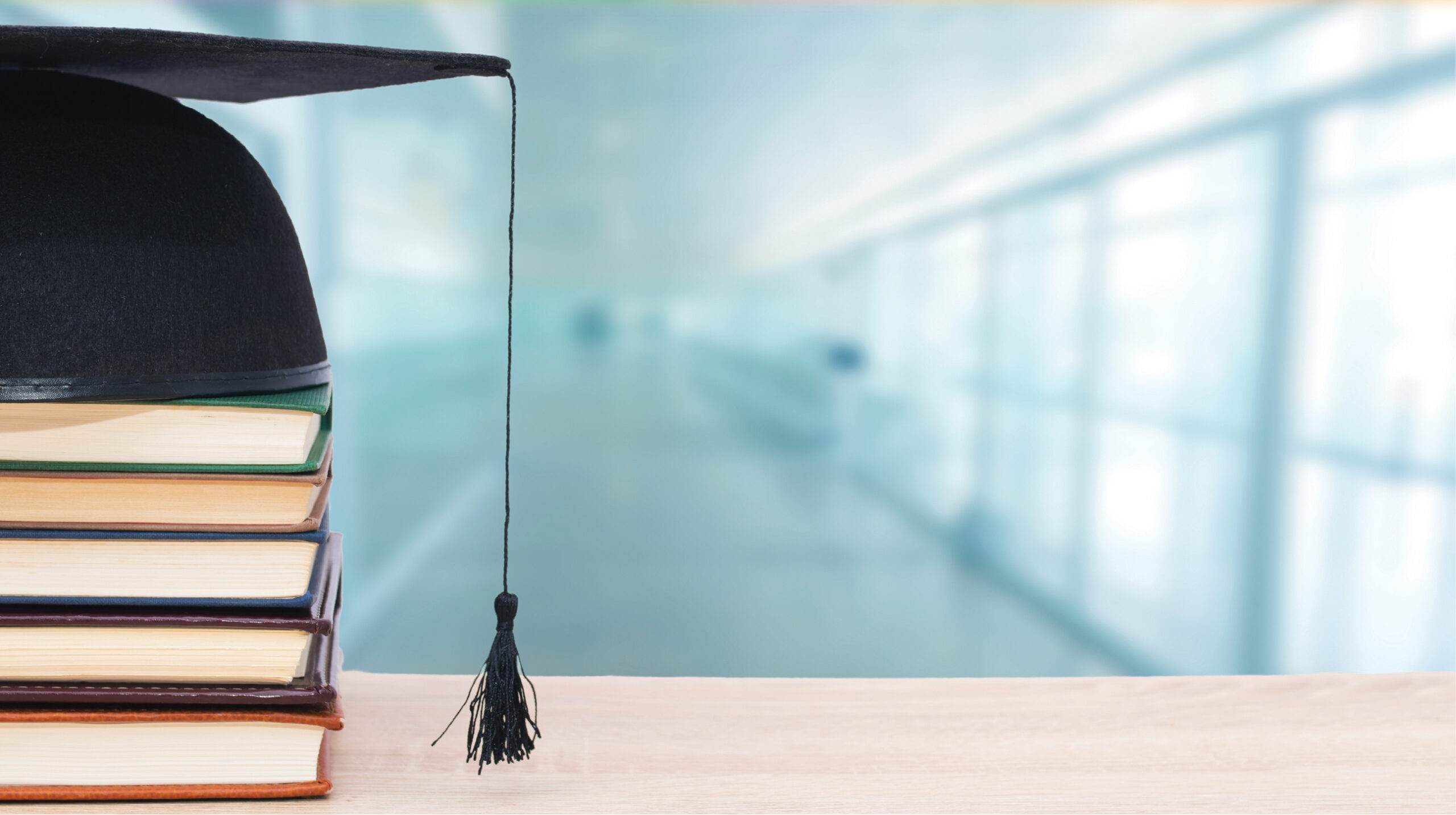 header of a mortarboard cap atop a stack of books