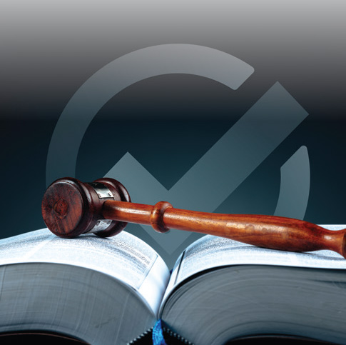 A wooden gavel lays across an opened textbook. The backdrop is solid black with a gray check mark.